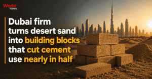 Stacked desert-sand building blocks with the Dubai skyline at sunset, World News graphic reading "Dubai firm turns desert sand into building blocks that cut cement use nearly in half"